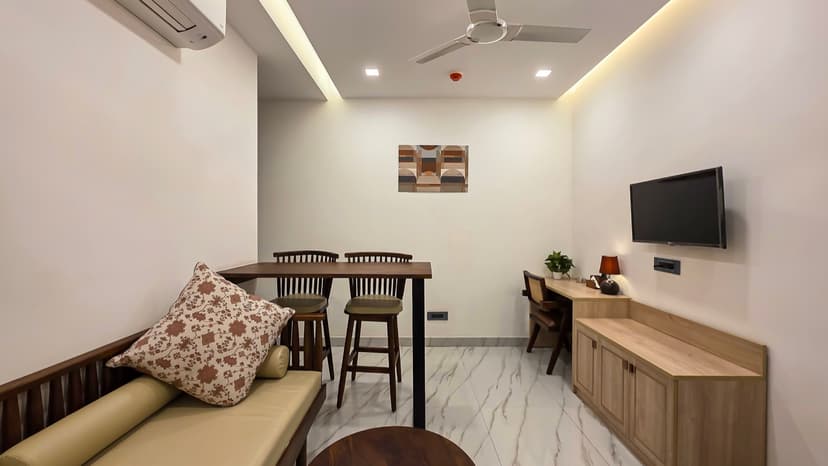 Living and dining area with sofa, bar seating, and wall-mounted TV